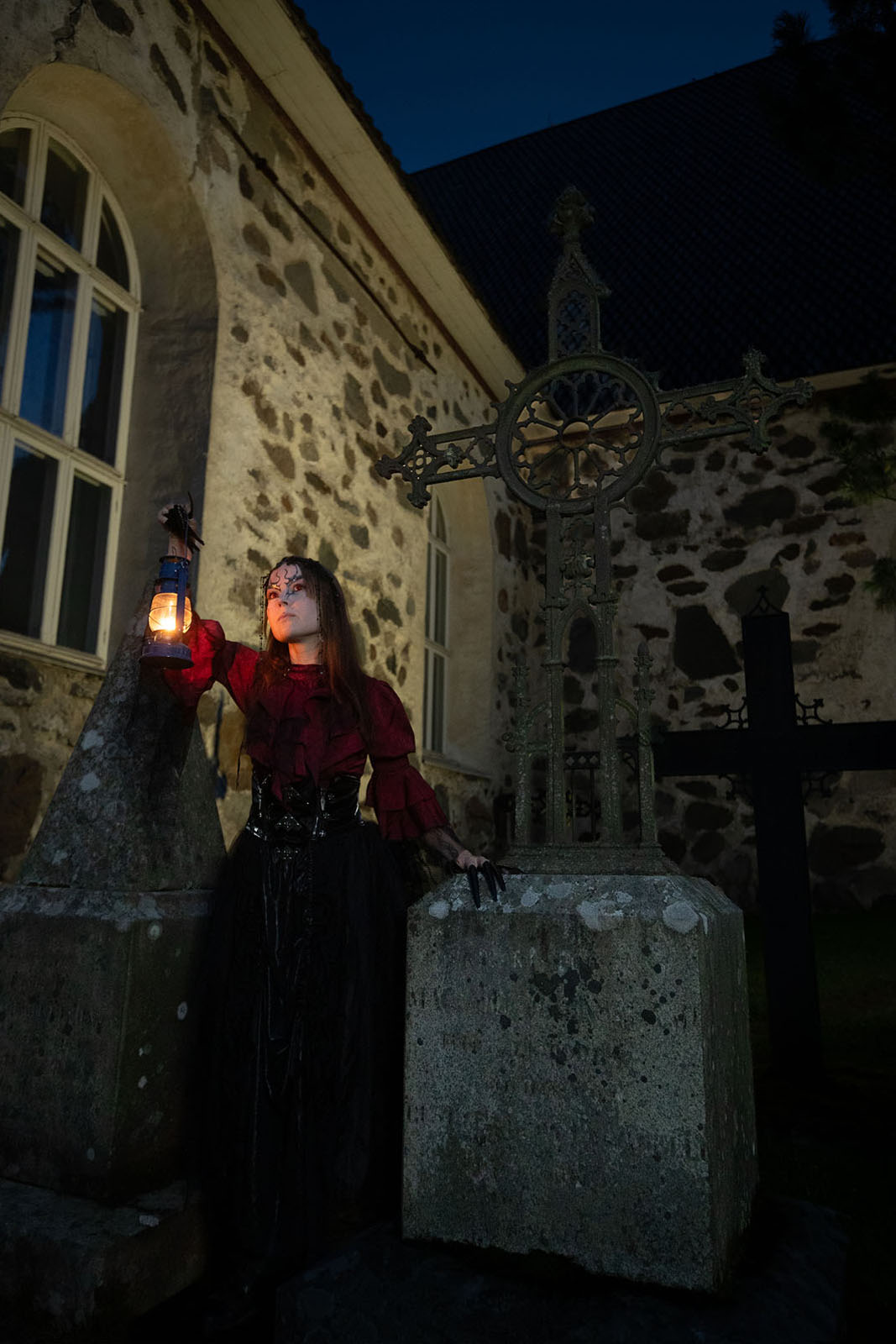 Vampire woman standing in grave yard with a lantern