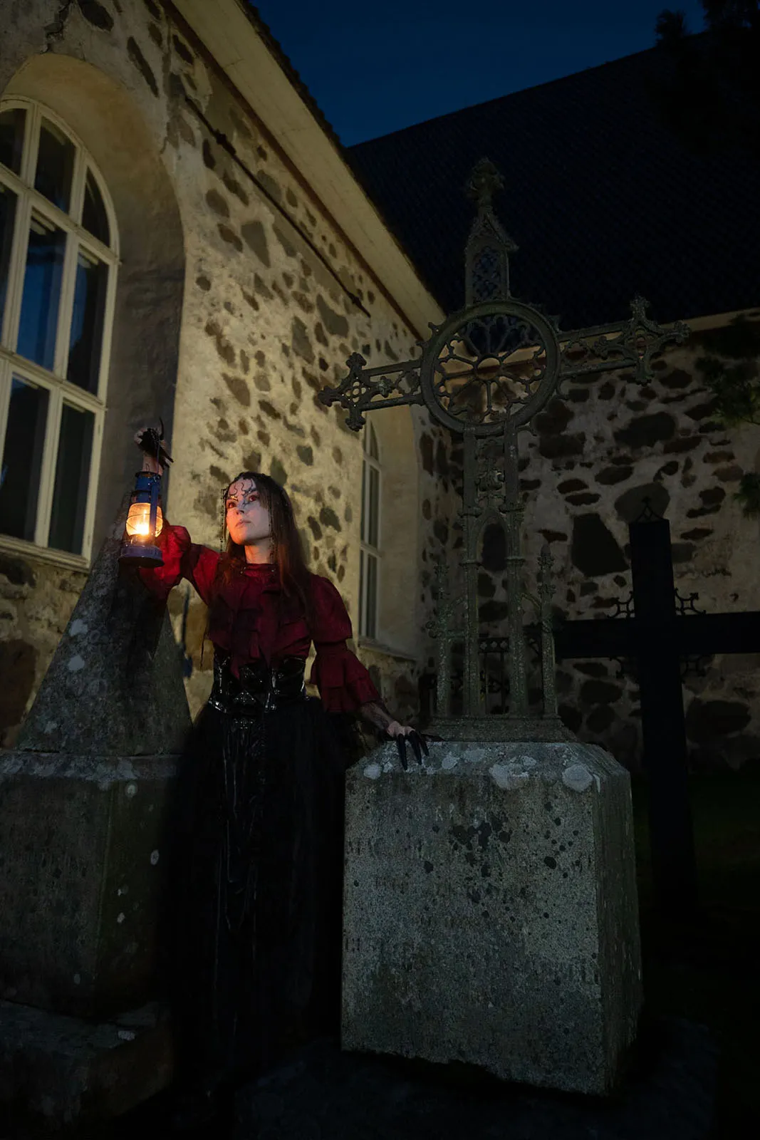 Vampyyrinainen seisoo hautausmaalla lyhty kädessään
